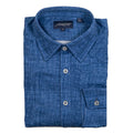 A folded blue chambray shirt with signature square buttons on the cuff, collar stays, and a tailored collar.