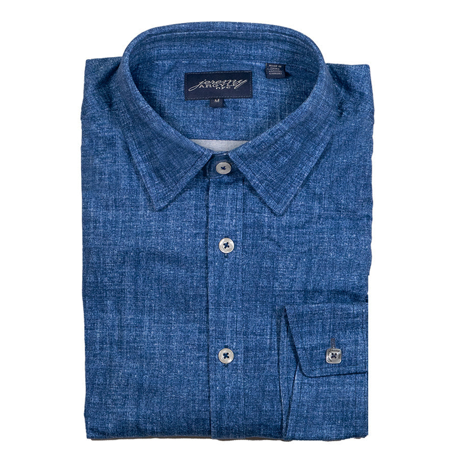 A folded blue chambray shirt with signature square buttons on the cuff, collar stays, and a tailored collar.